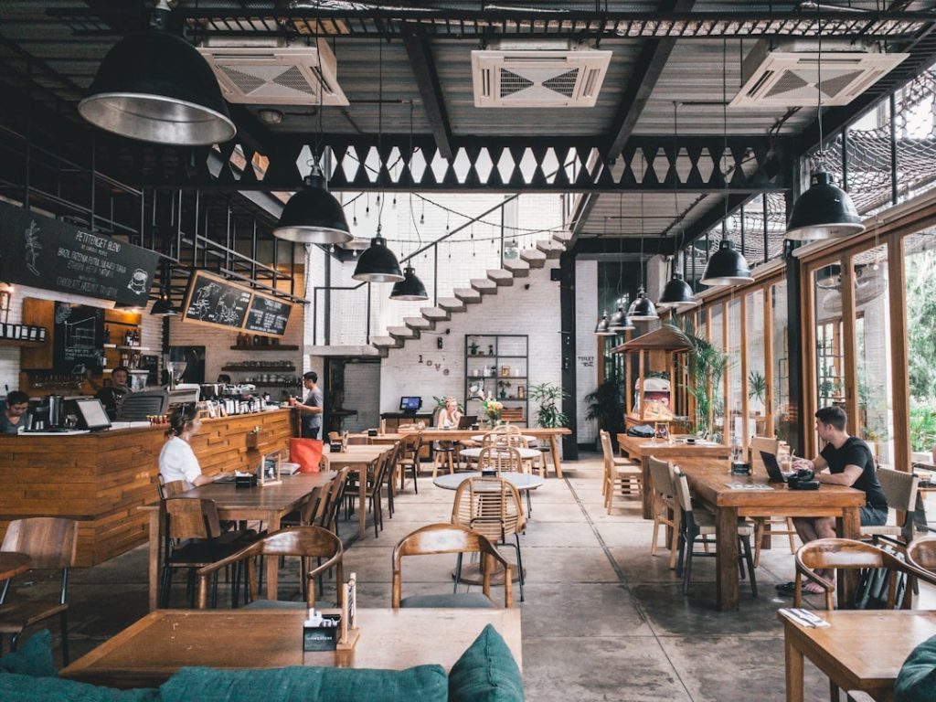 Freelancer Indonesia sedang bekerja di kafe dengan laptop dan catatan keuangan
