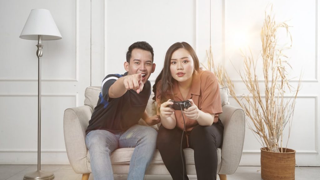 Pasangan muda Indonesia memegang kunci model rumah dan celengan babi untuk tabungan
