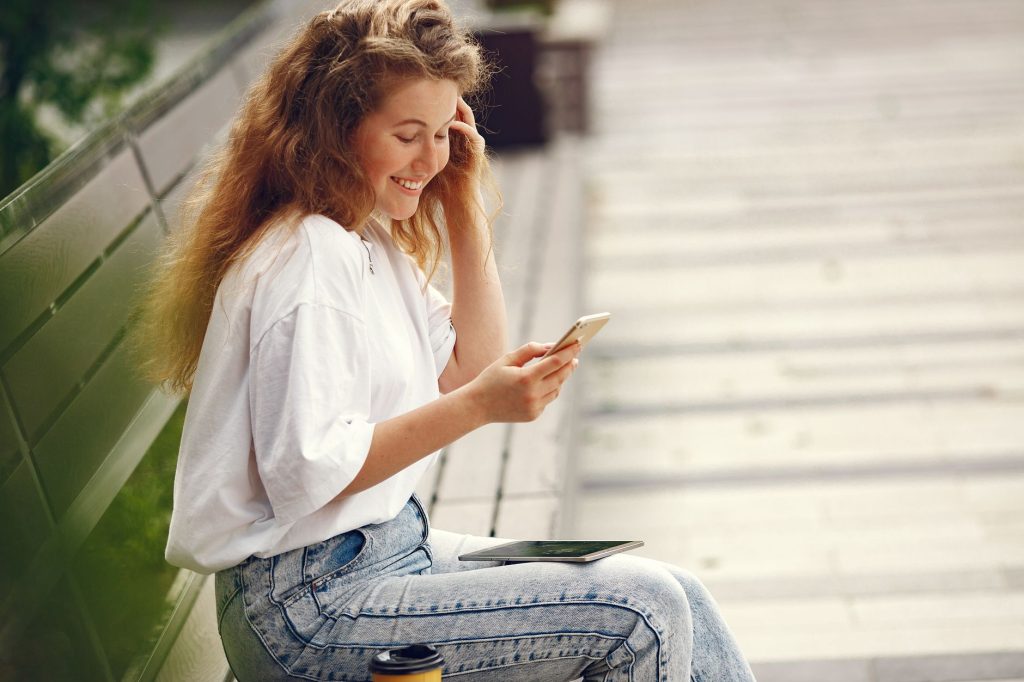 Wanita muda sedang memeriksa pengeluaran di e‑wallet menggunakan smartphone.