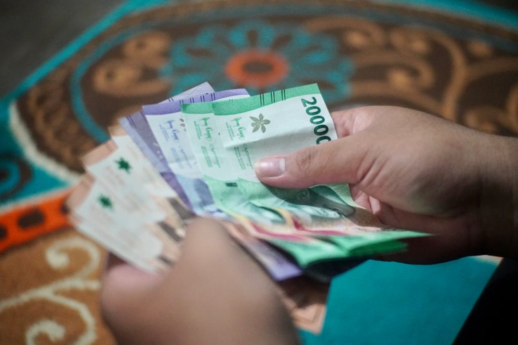 Seseorang menghitung uang THR rupiah di meja