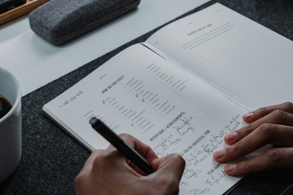 Mahasiswa sedang menulis catatan anggaran di notebook
