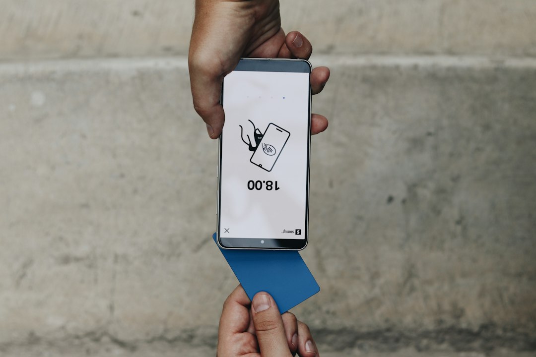 Tangan memegang smartphone menampilkan layar transfer